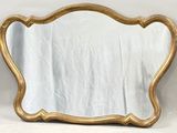 un miroir à cadre doré posé sur une table blanche