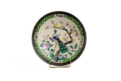 une assiette ornée d'un paon, posée sur un socle