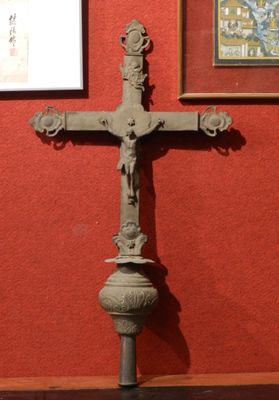 a cross on a pedestal in front of a red wall