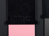 a close up of a knife and a pink sticky pad on a black surface