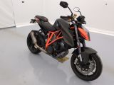 une moto noire et orange garée dans une pièce blanche