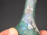 a hand holding a piece of glass with a green and blue design on it