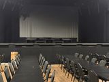 rows of chairs in a large auditorium with a projector screen in the background