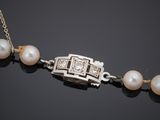 a close up of a necklace with pearls on a black surface