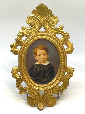 portrait d'un jeune garçon vêtu d'une robe noire, dans un cadre doré