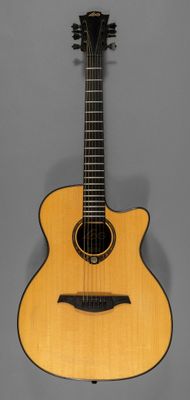 une guitare acoustique posée sur un support, sur fond gris
