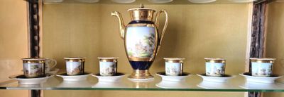 une étagère en verre sur laquelle sont posées des tasses et un vase