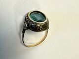 une bague sertie d'une pierre verte sur un fond blanc