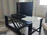 a glass coffee table with a television on it in a living room