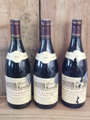 three bottles of wine are lined up on a wooden shelf