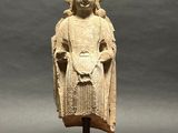 an old statue of a woman with a robe on a wooden stand