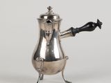une cafetière ancienne en argent avec une poignée noire sur fond blanc