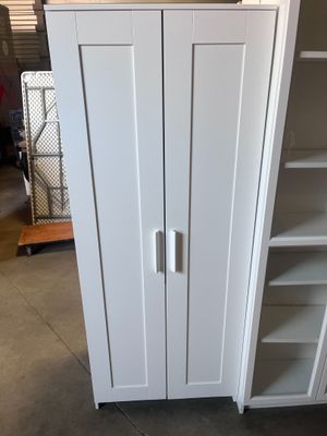 a white cabinet with a door and shelves in the room