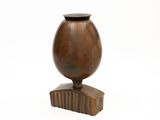 a wooden vase with a black lid on a stand