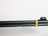 a close up of a gun on a white surface with a yellow handle