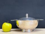 an apple next to a silver bowl on a table