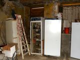 three refrigerators and a ladder in a dirty room