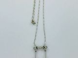 un collier en argent auquel sont suspendues deux clochettes