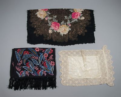 three pieces of cloth with flowers and fringes are on a table