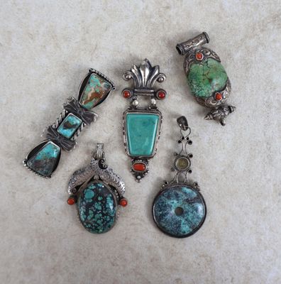 cinq bijoux en turquoise et en corail posés sur un fond blanc