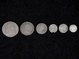 several silver coins are arranged in a row on a black surface