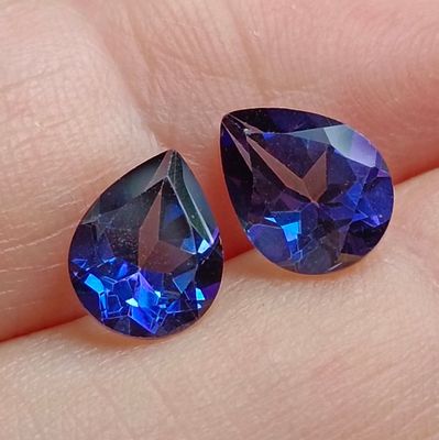 pair of blue sapphires on a person ' s finger