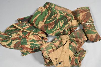 un tas de vêtements de camouflage posé sur une surface blanche