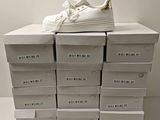 une pile de cartons sur laquelle est posée une paire de chaussures blanches