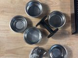 a wooden table topped with metal measuring cups and measuring spoons