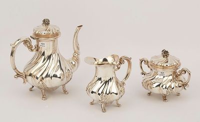 three pieces of silver tea and coffee set on a white surface