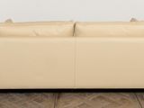an image of a beige leather couch sitting on top of a hard wood floor