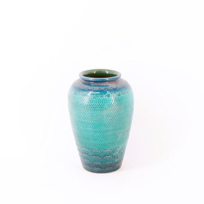 un vase bleu posé sur une surface blanche