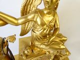 une statue en or représentant un ange tenant un oiseau, posée sur une table