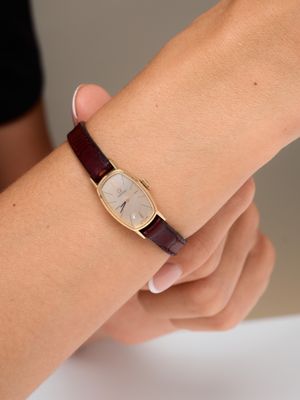 Quelqu'un tient un poignet sur lequel se trouve une montre, posé sur une table.