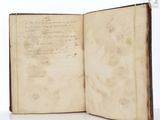 an old open book with writing on it sitting on a table