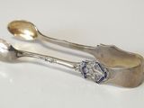 deux cuillères en argent et un repose-cuillère posés sur une surface blanche