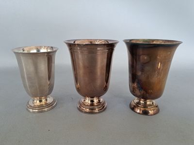 trois vases en argent posés les uns à côté des autres sur une table