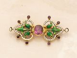 a close up of a brooch with a pink stone