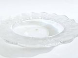 un bougeoir en verre transparent posé sur une surface blanche