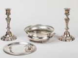 three silver candlesticks and a bowl on a white surface