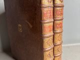 two old books sitting on top of a table next to each other