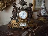 une horloge posée sur une table, à côté d'un vase