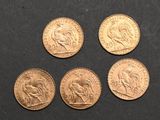 four different types of gold coins on a black surface