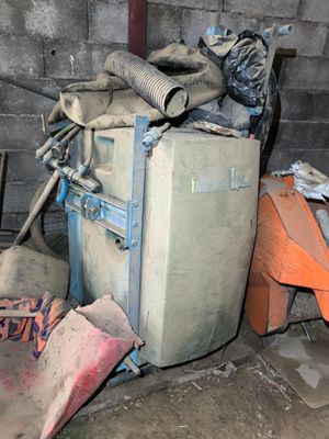 a pile of garbage in a dirty room with a pile of shovels on the floor