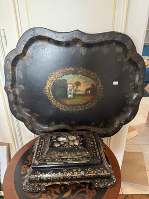 un plateau noir orné d'une peinture, posé sur une table en bois