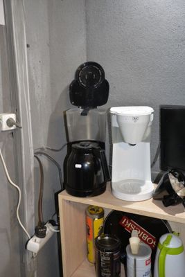 a coffee maker and other items on a shelf in the corner of a room