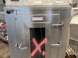 un four en métal sur lequel est dessiné un X rouge, dans un entrepôt