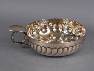 une assiette ancienne en argent avec une anse, sur fond gris