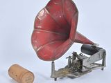 un gramophone rouge et argent à côté d'un bouchon en liège