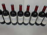 six bottles of red wine are lined up on a table